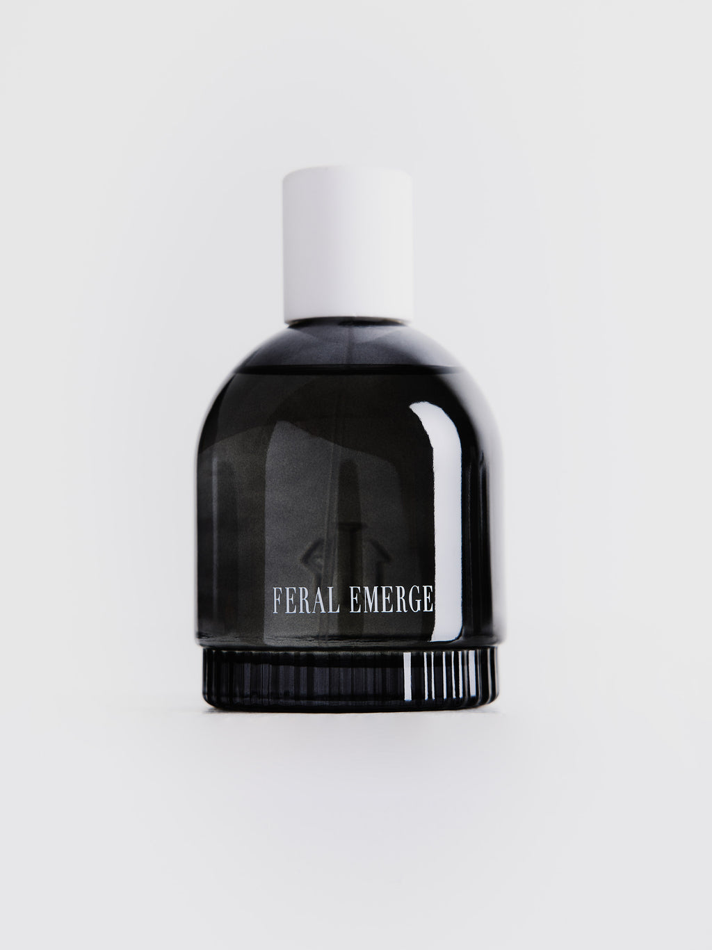 Smal dark gray transparent perfume bottle, with "FERAL EMERGE" label and white cap on top 